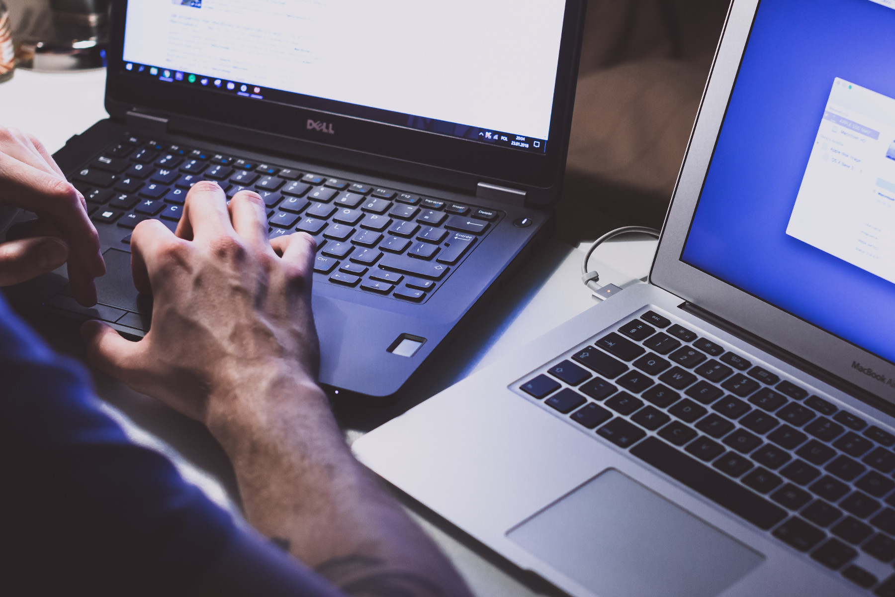 hands typing on a laptop with another laptop by the side